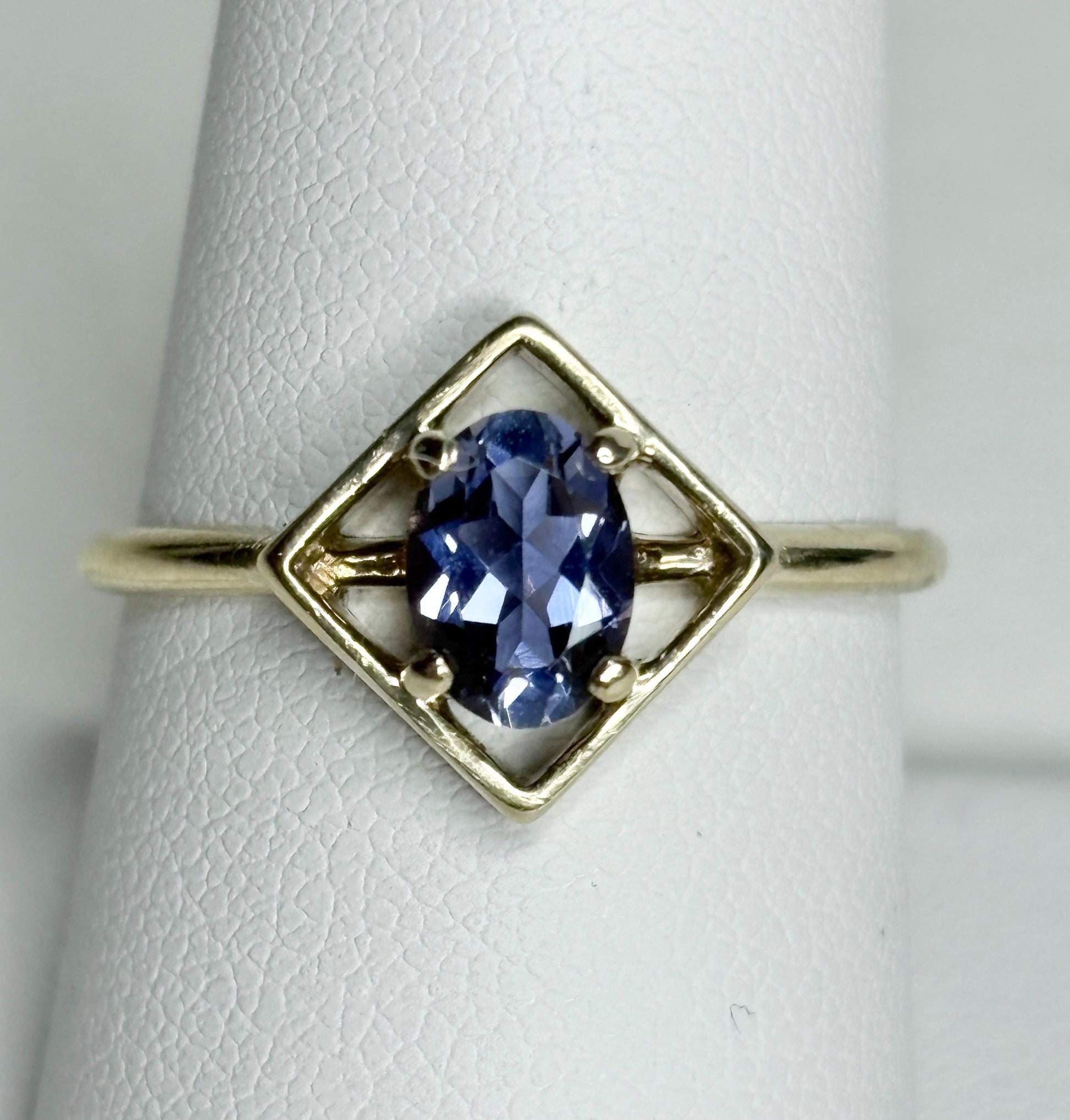 A 10k gold ring with a geometric setting holding an oval iolite.
