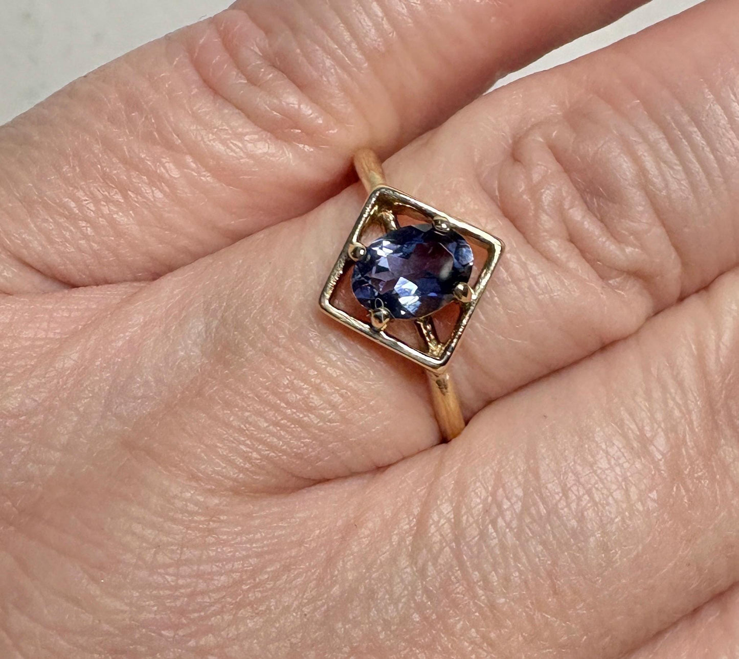 A 10k gold ring with a square setting holding an oval iolite gemstone.