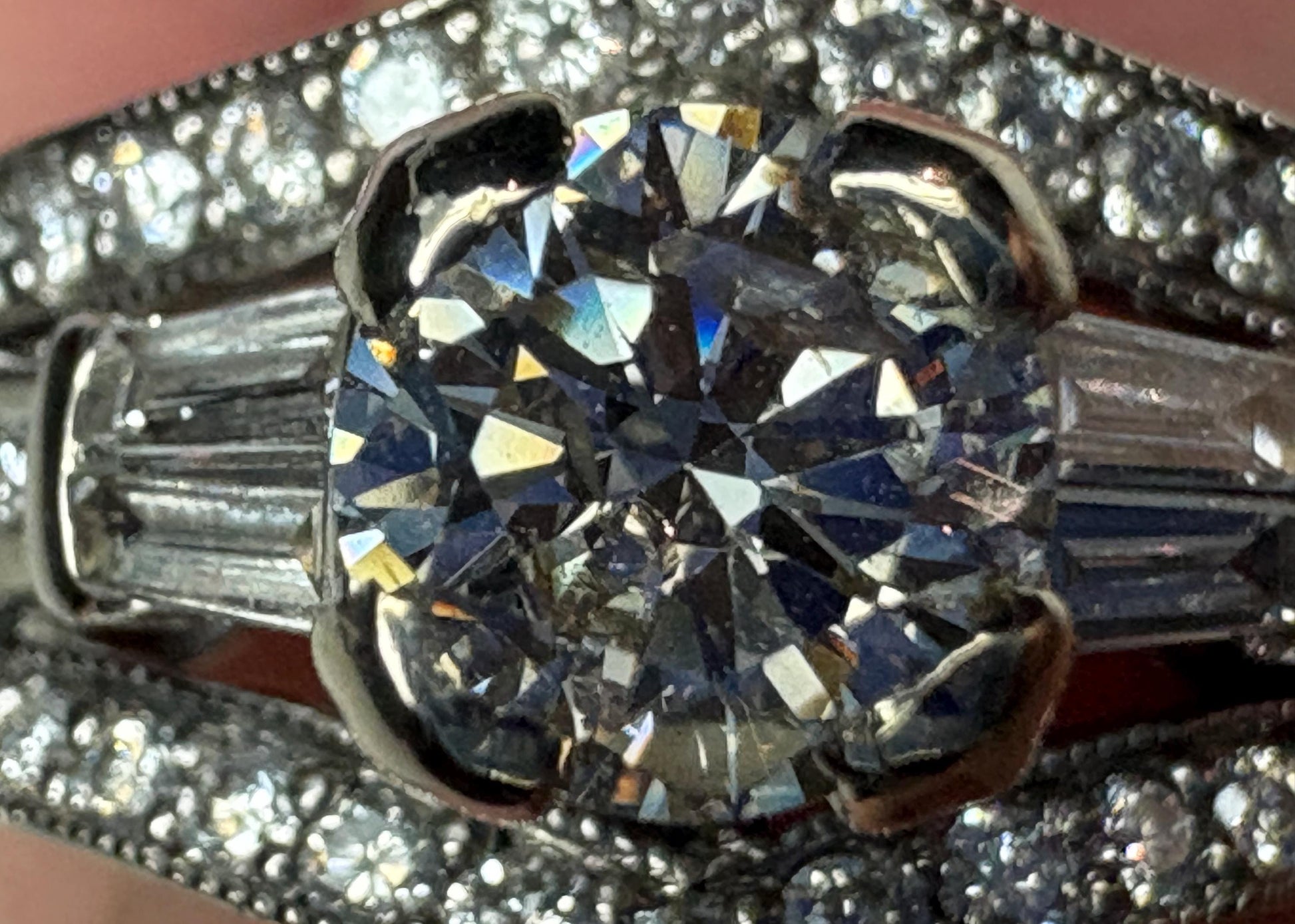 A 14k white gold ring with a central diamond and baguette and round accent diamonds.