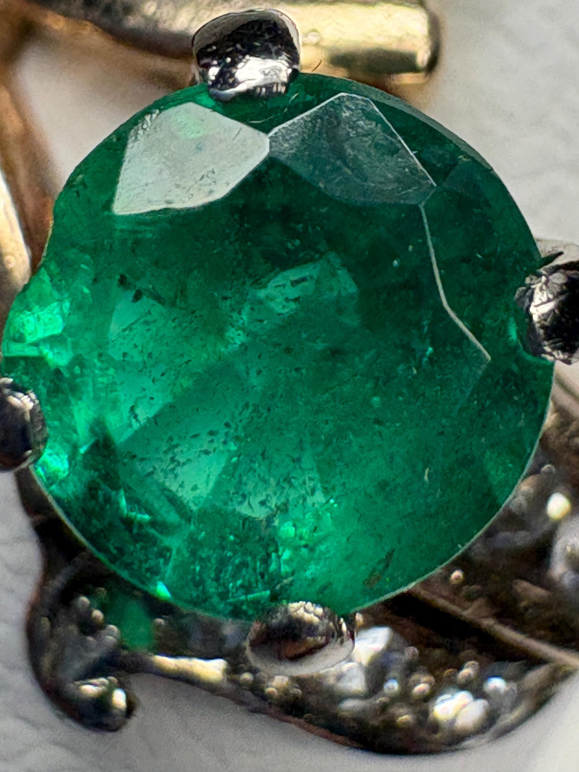 A vintage 14k gold ring featuring a free-form emerald and single cut diamonds.