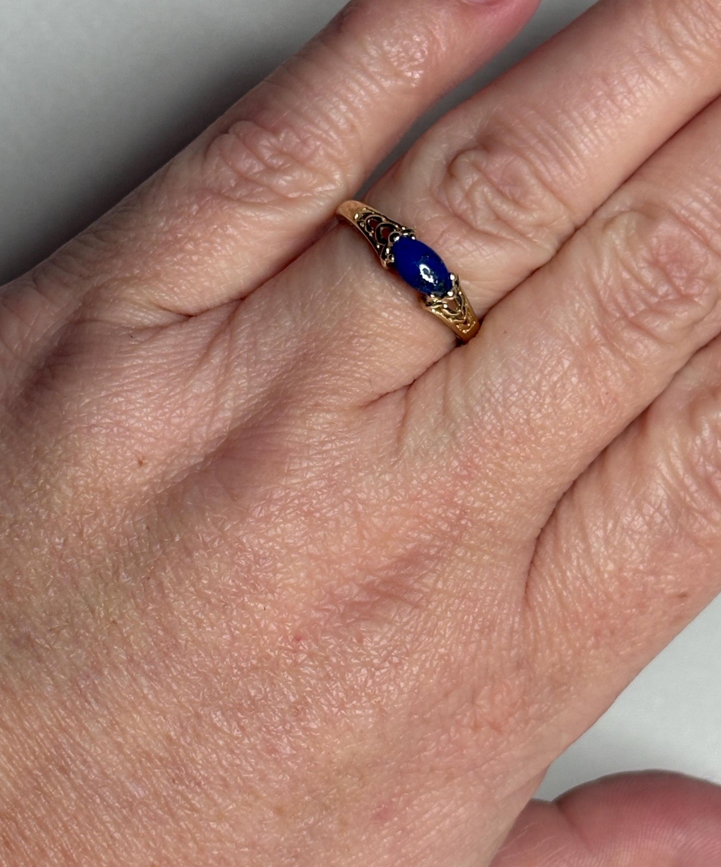 A 14k gold ring with a marquise lapis lazuli cabochon set east west.