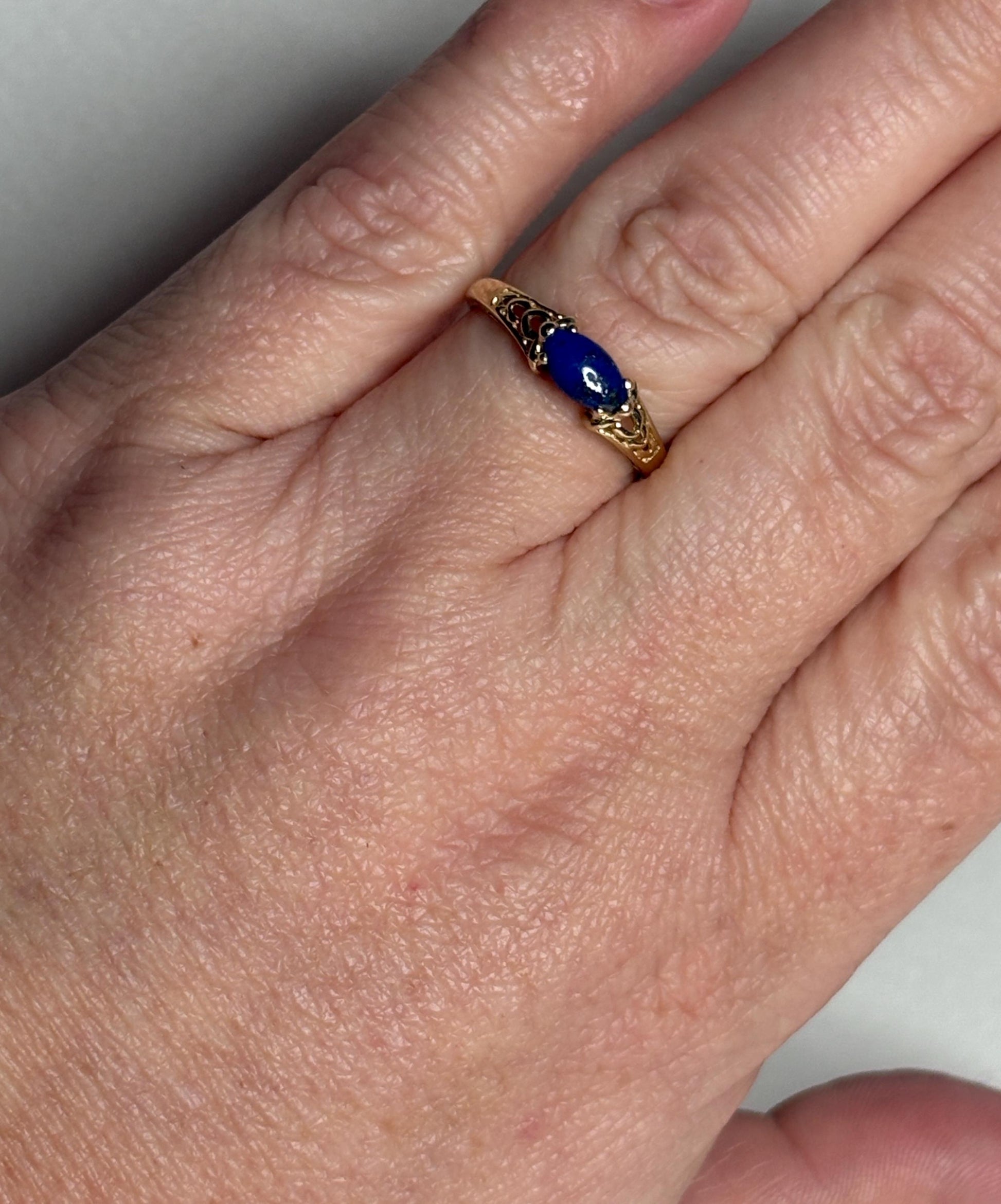 A 14k gold ring with a marquise lapis lazuli cabochon set east west.