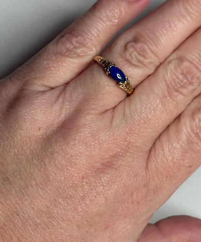 A 14k gold ring with a marquise lapis lazuli cabochon set east west.