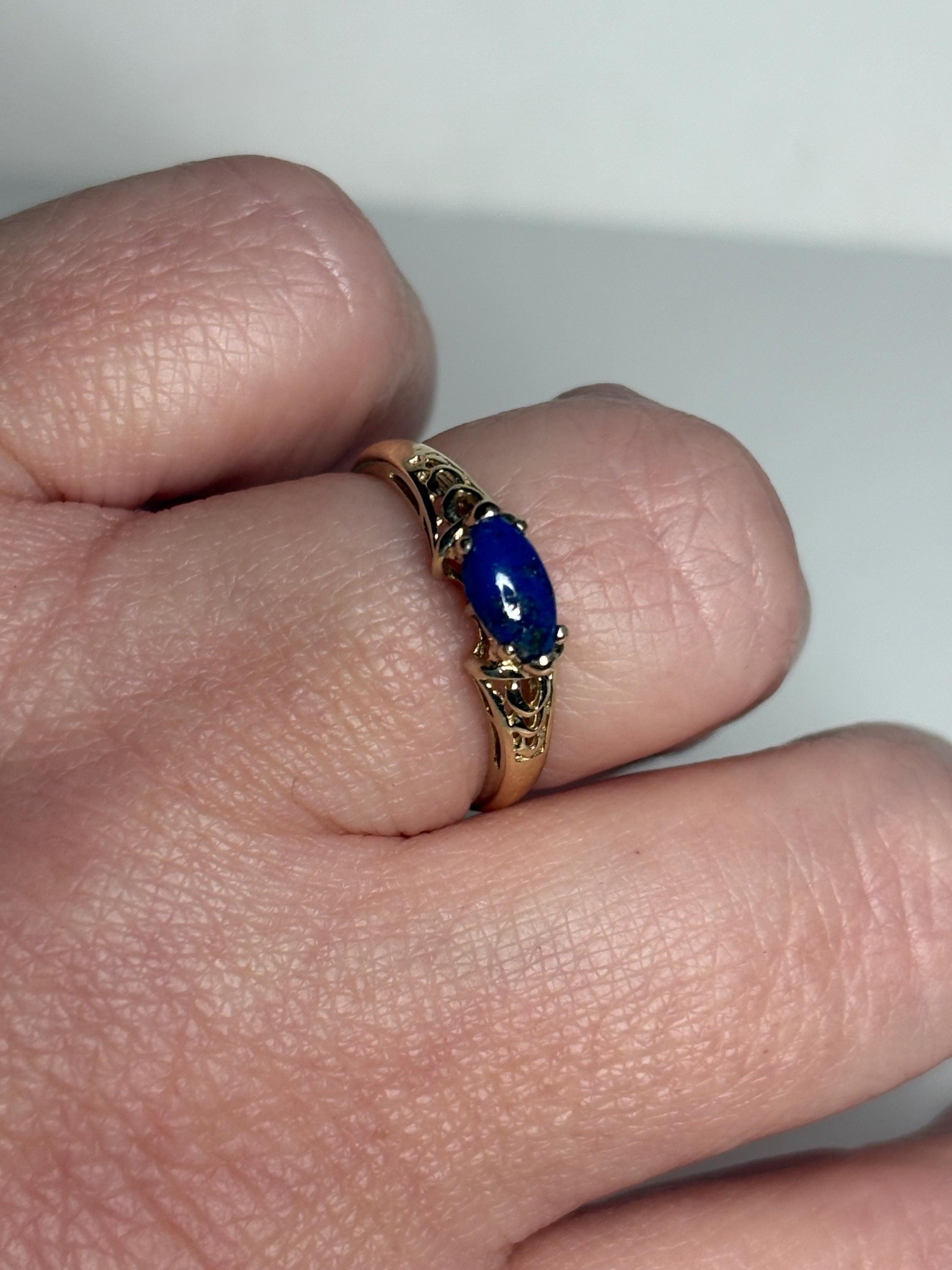 A 14k gold ring with a marquise lapis lazuli cabochon set east west.