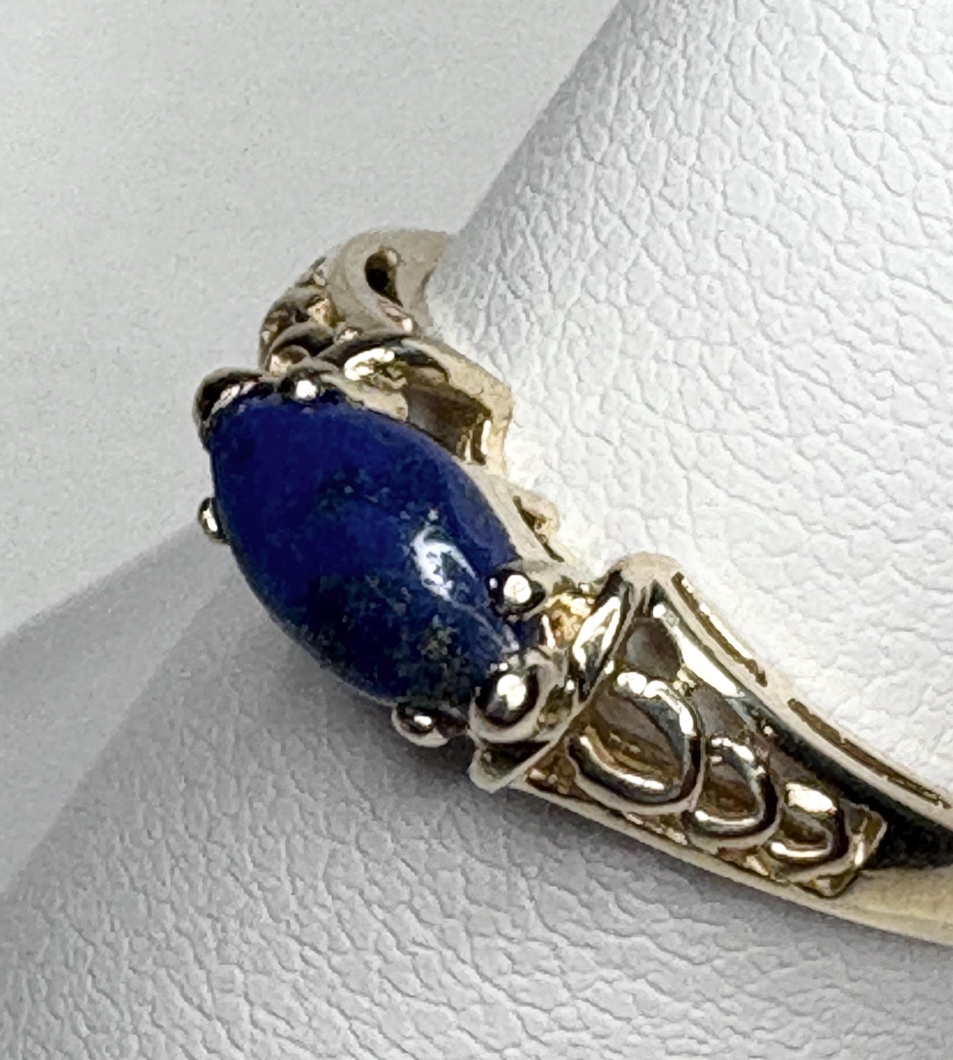 A 14k gold ring with an east-west set marquise lapis lazuli cabochon.