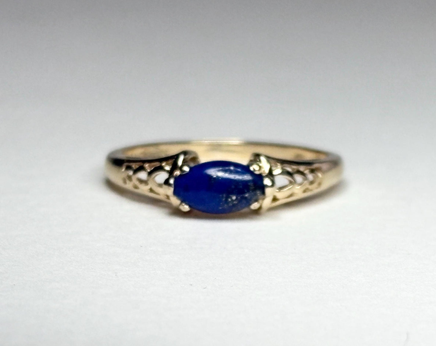 A 14k gold ring with an east-west set oval lapis lazuli cabochon.