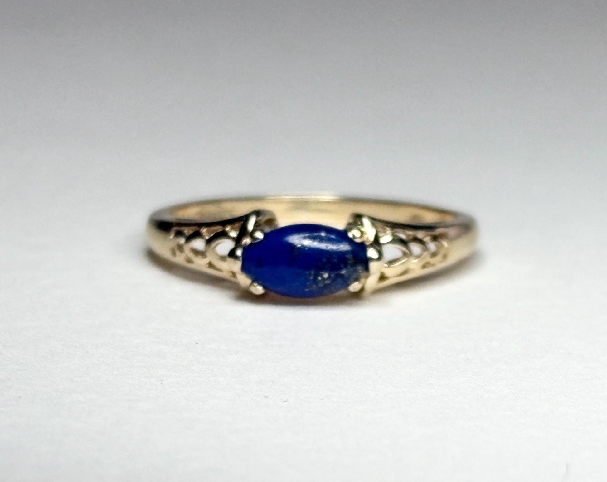 A 14k gold ring with an east-west set oval lapis lazuli cabochon.