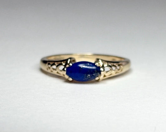 A 14k gold ring with an east-west set oval lapis lazuli cabochon.