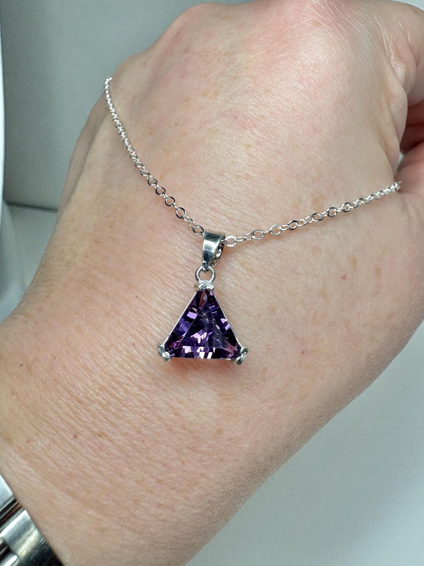 Sterling silver pendant necklace with a triangular amethyst gemstone.