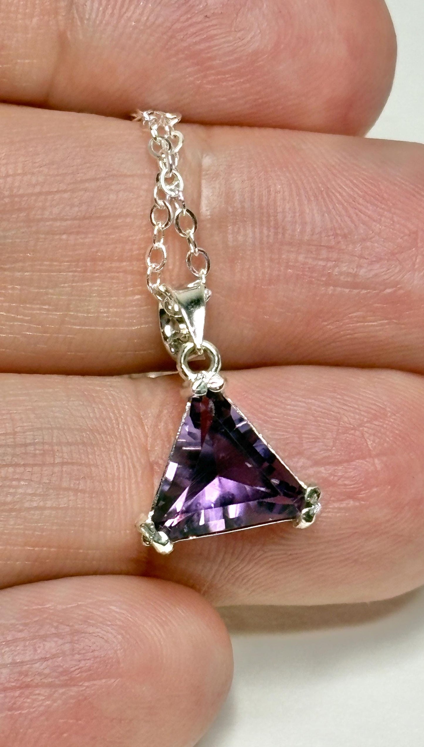 Sterling silver pendant necklace with a triangular amethyst gemstone.
