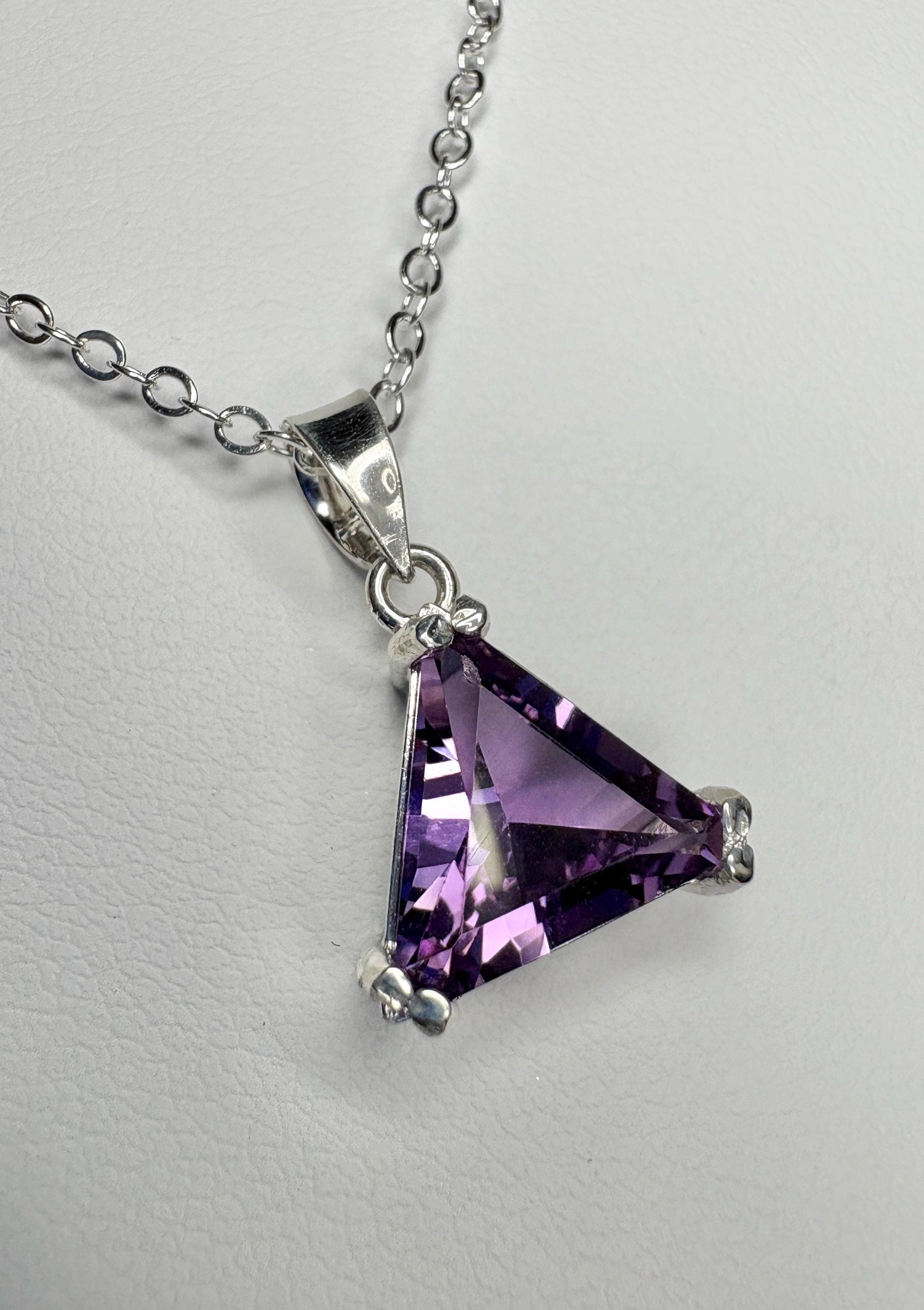 Sterling silver pendant necklace with a triangular amethyst gemstone.