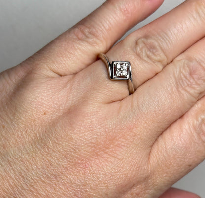 A 10k white gold ring with a square diamond cluster and milgrain detail.