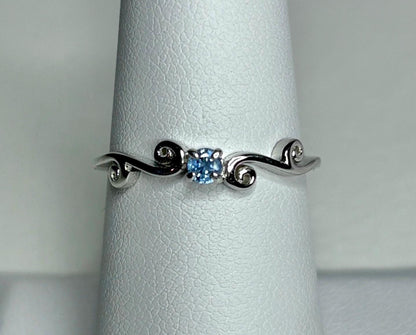 Sterling silver ring with a light blue sapphire and swirl band.
