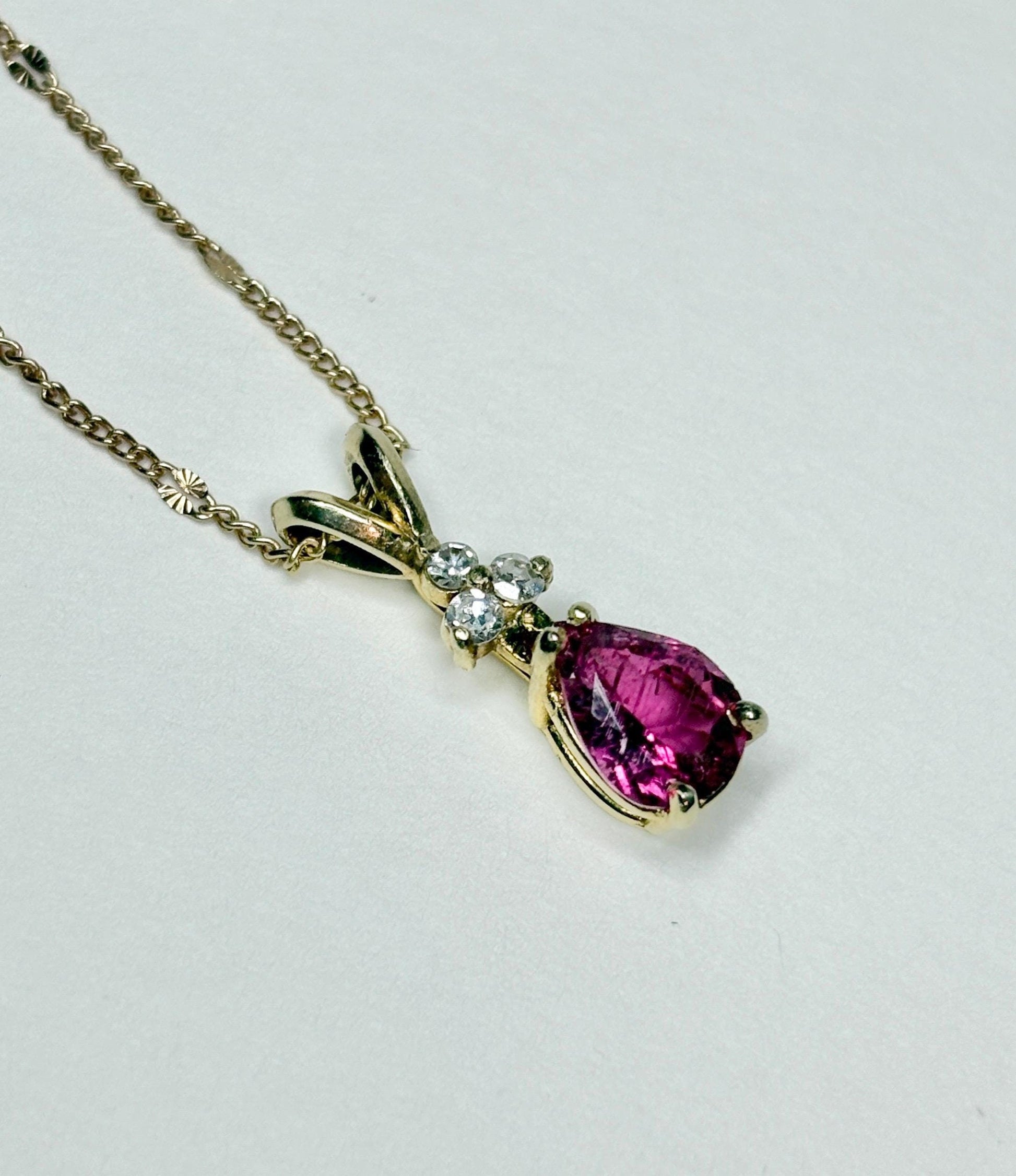 A 14k gold necklace with a pear-shaped rubellite tourmaline pendant and diamond accents.