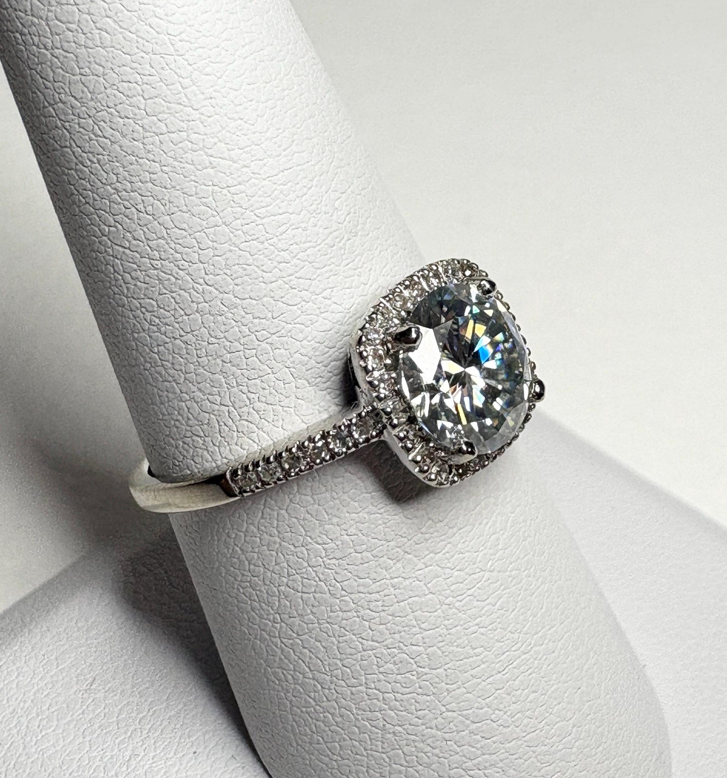 Oval moissanite halo ring with diamond accents in white gold.