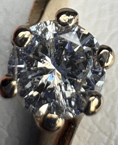 A solitaire diamond ring with a twist design in 14k gold.