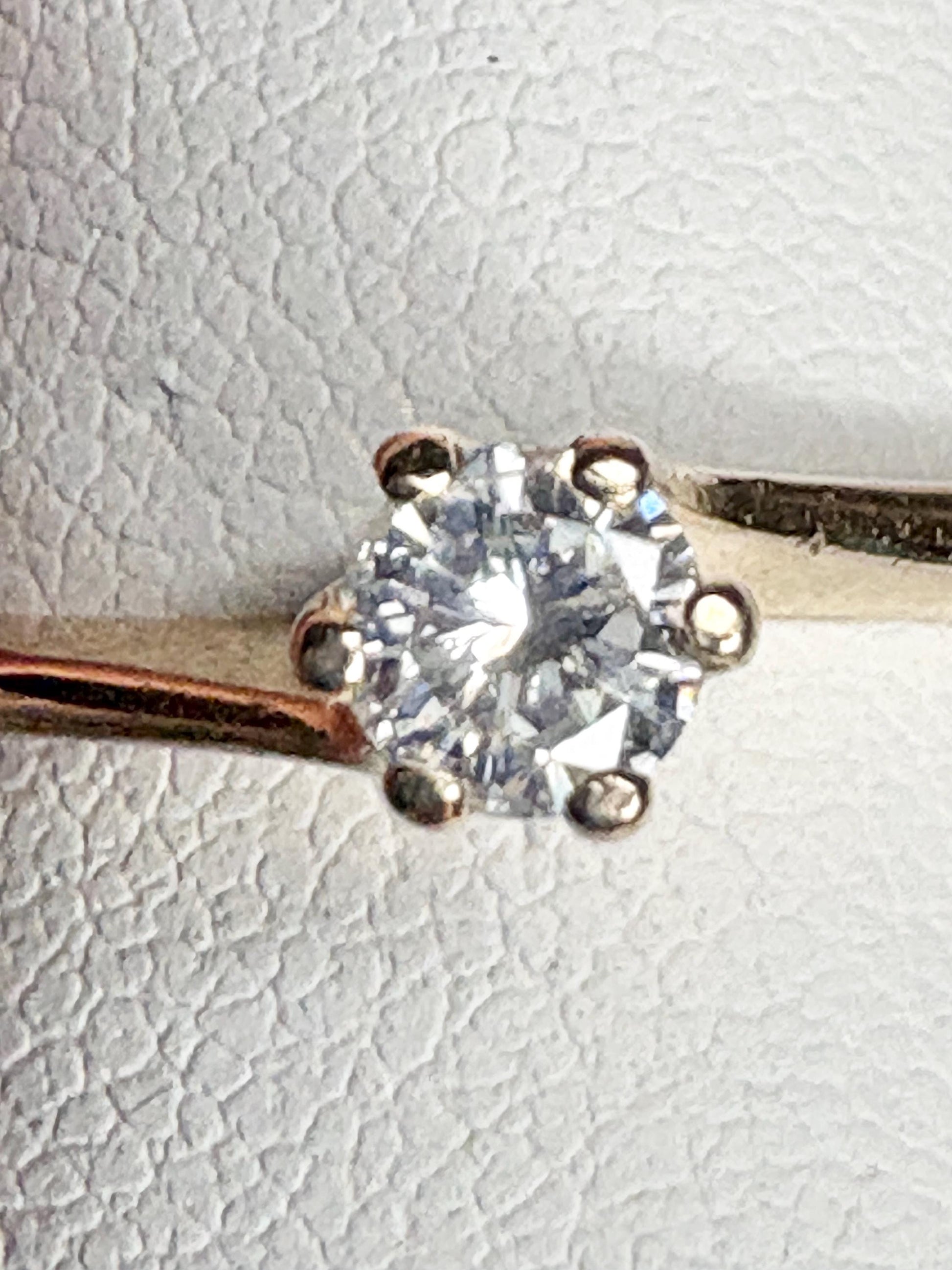 A solitaire diamond ring with a twist design in 14k gold.