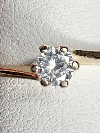 A solitaire diamond ring with a twist design in 14k gold.