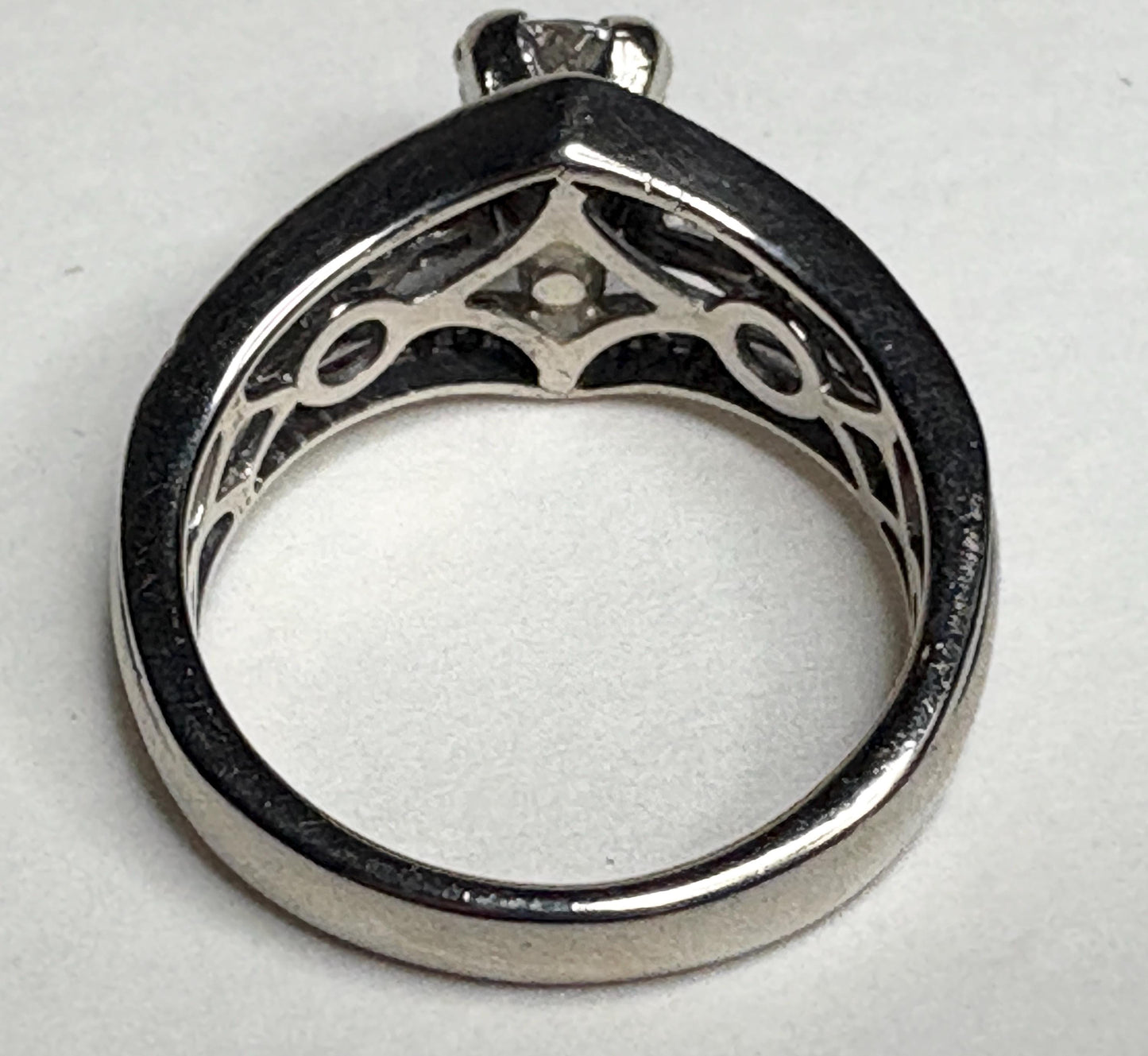 A 14k white gold ring with a center diamond and intricate detailing.