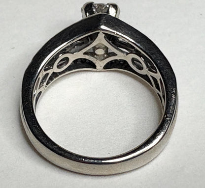 A 14k white gold ring with a center diamond and intricate detailing.