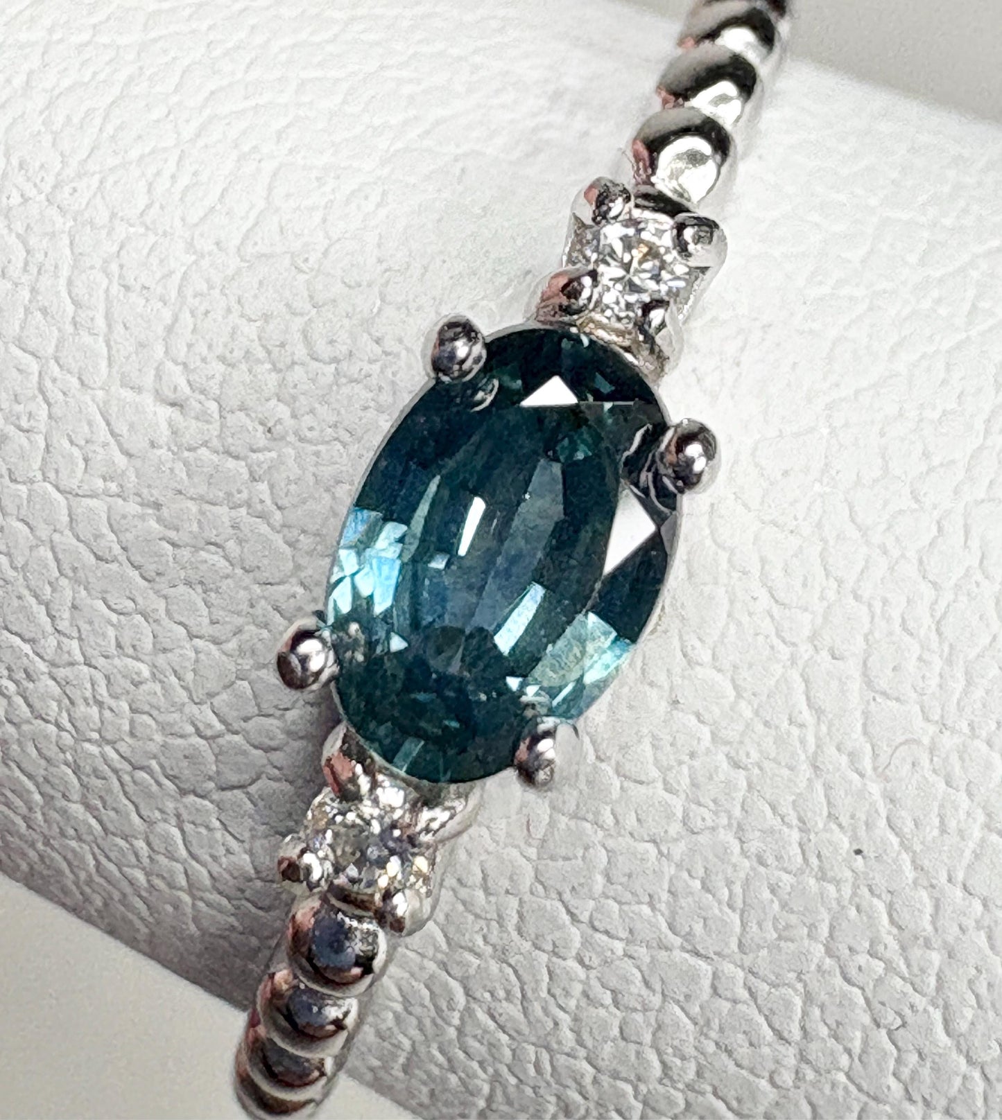 Sterling silver ring with oval Montana sapphire and two diamonds on a beaded band.