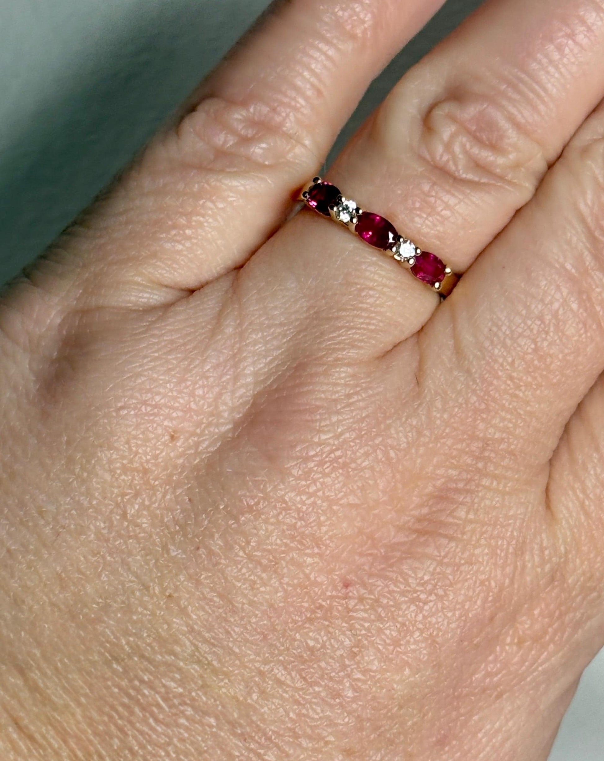 A 14k gold band ring with oval red sapphires and diamonds.