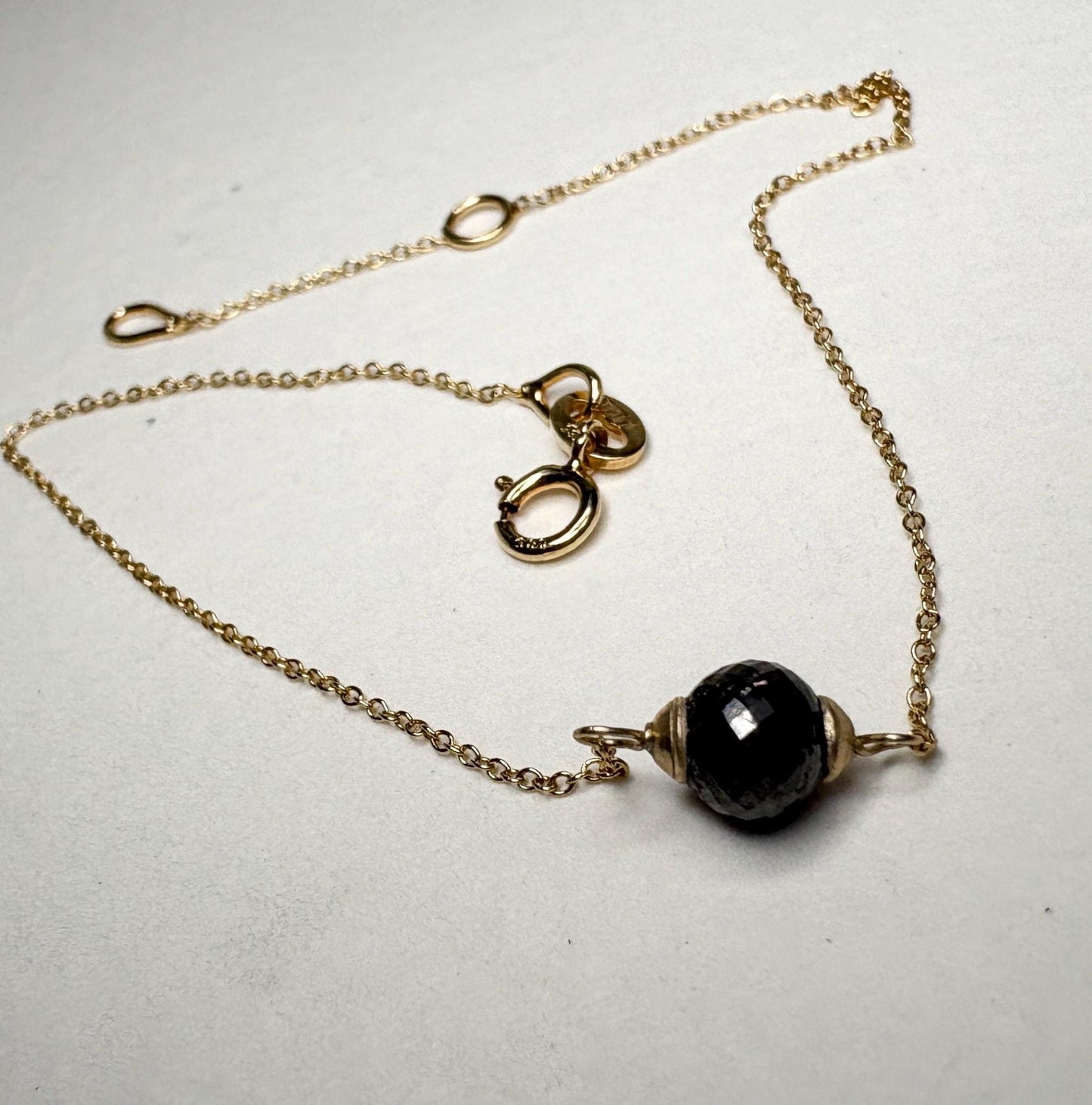 Solid 14k gold bracelet with a faceted black diamond bead.