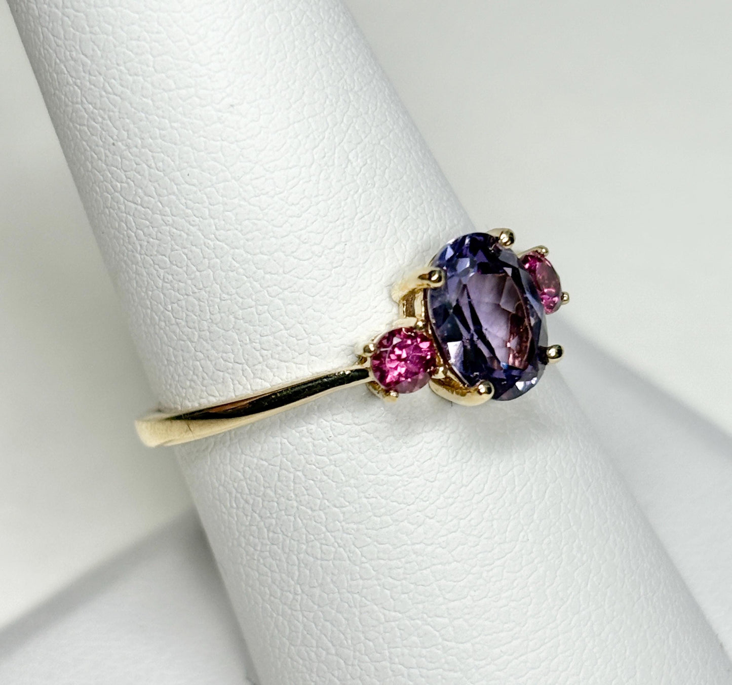A 10k gold ring with a color-change synthetic sapphire and two umbalite garnets.