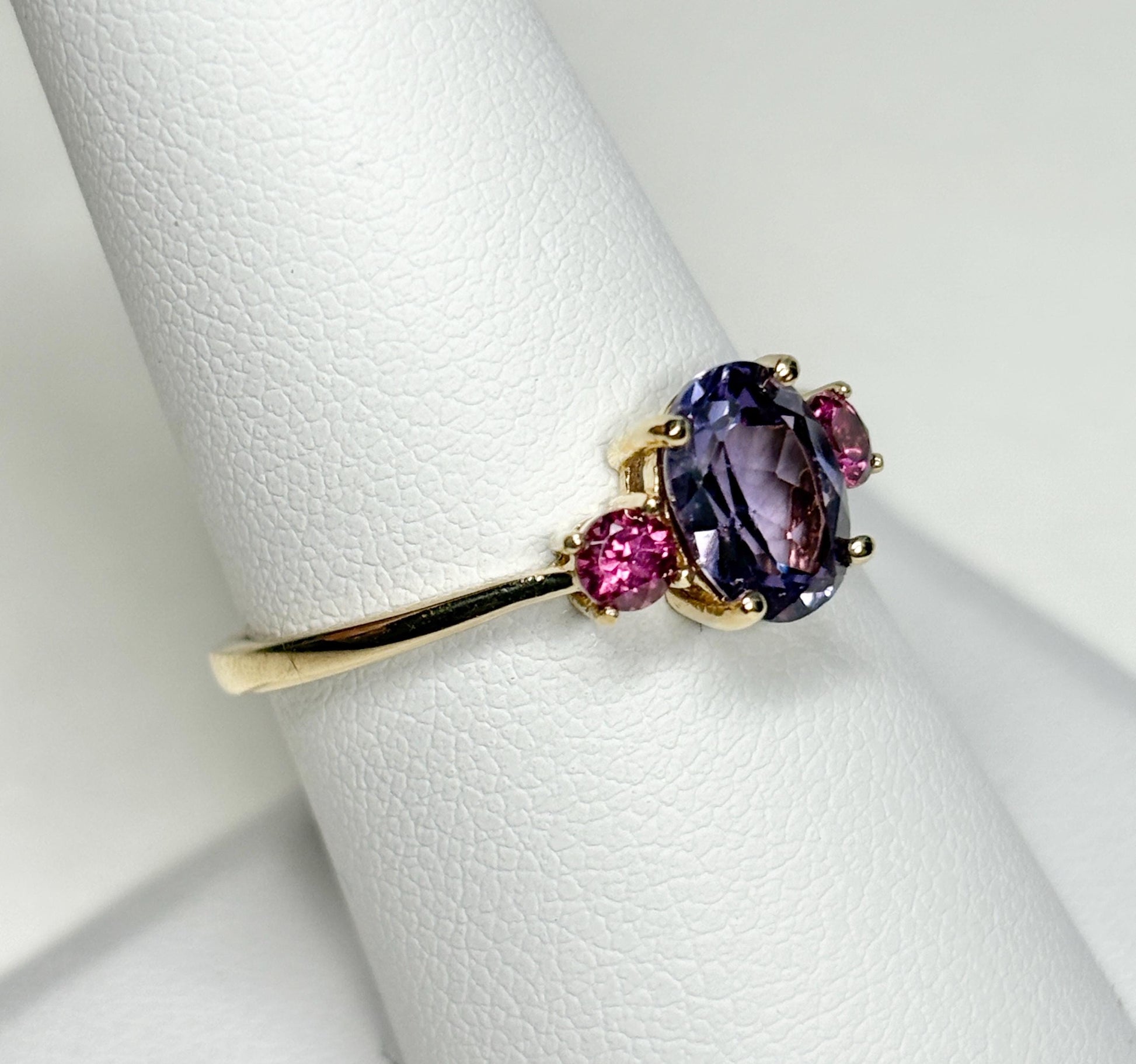 A 10k gold ring with a color-change synthetic sapphire and two umbalite garnets.