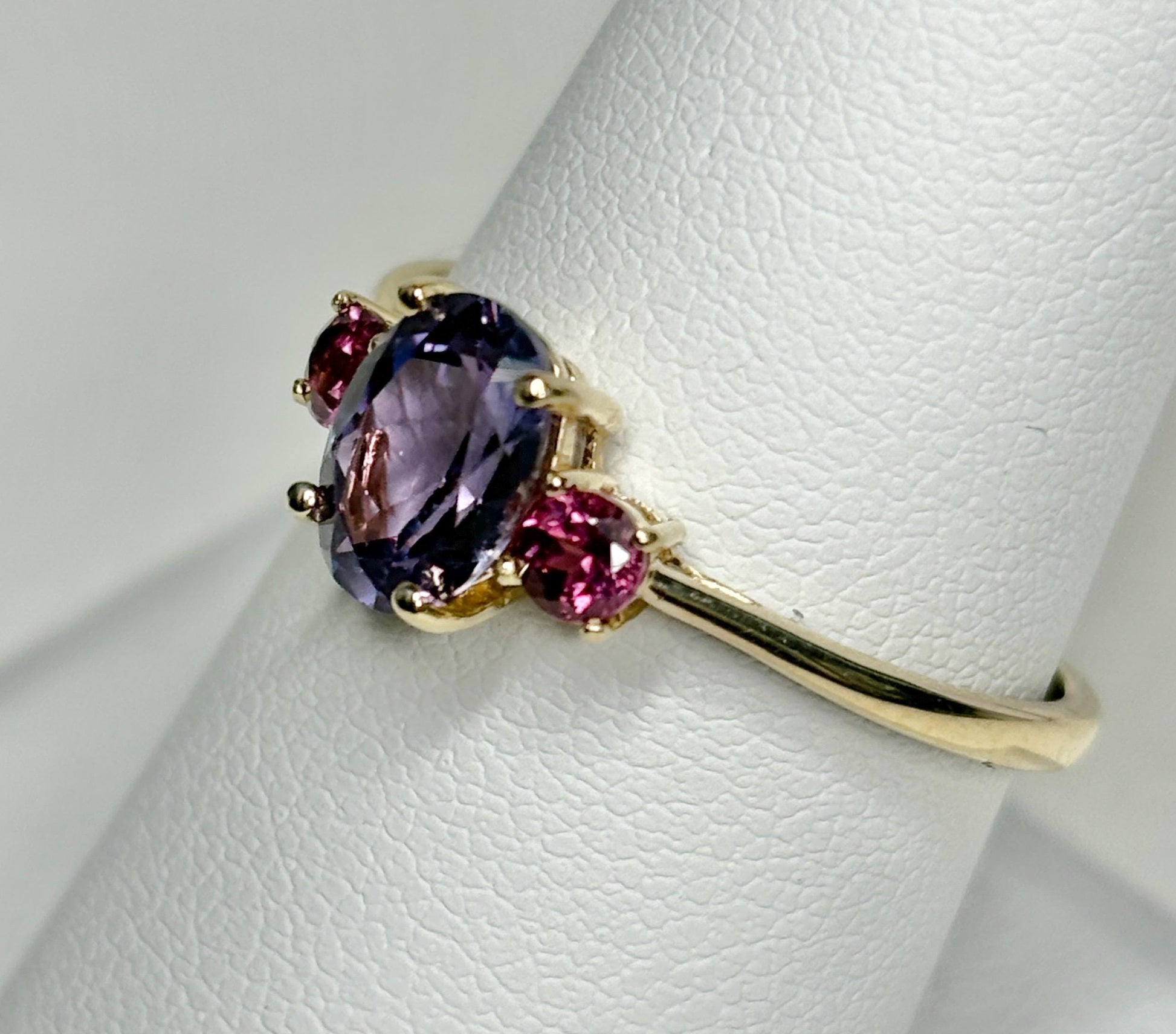 Ring with oval color change synthetic sapphire and two round garnets in gold.