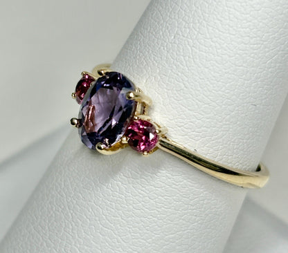 Ring with oval color change synthetic sapphire and two round garnets in gold.