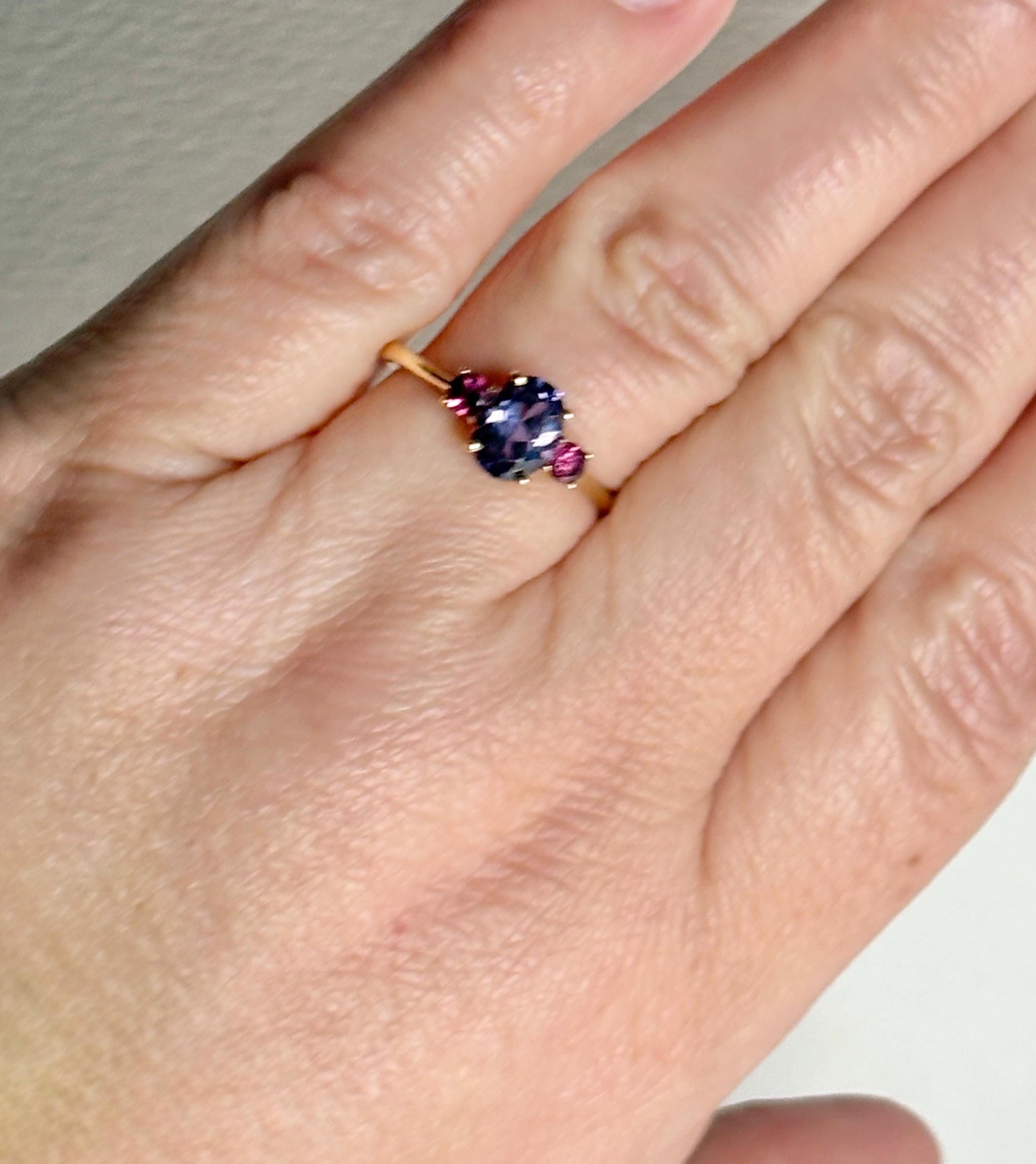A 10k gold ring with a color-changing synthetic sapphire and two umbalite garnets.