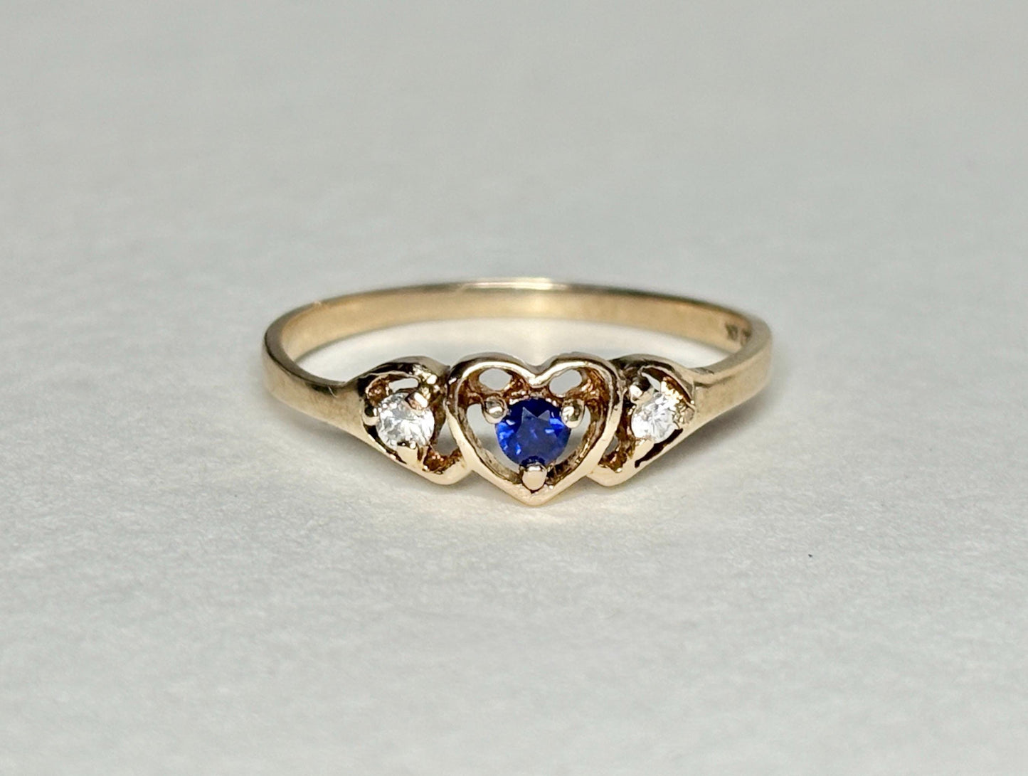 A vintage 10k gold heart band ring with a blue sapphire and two diamonds.