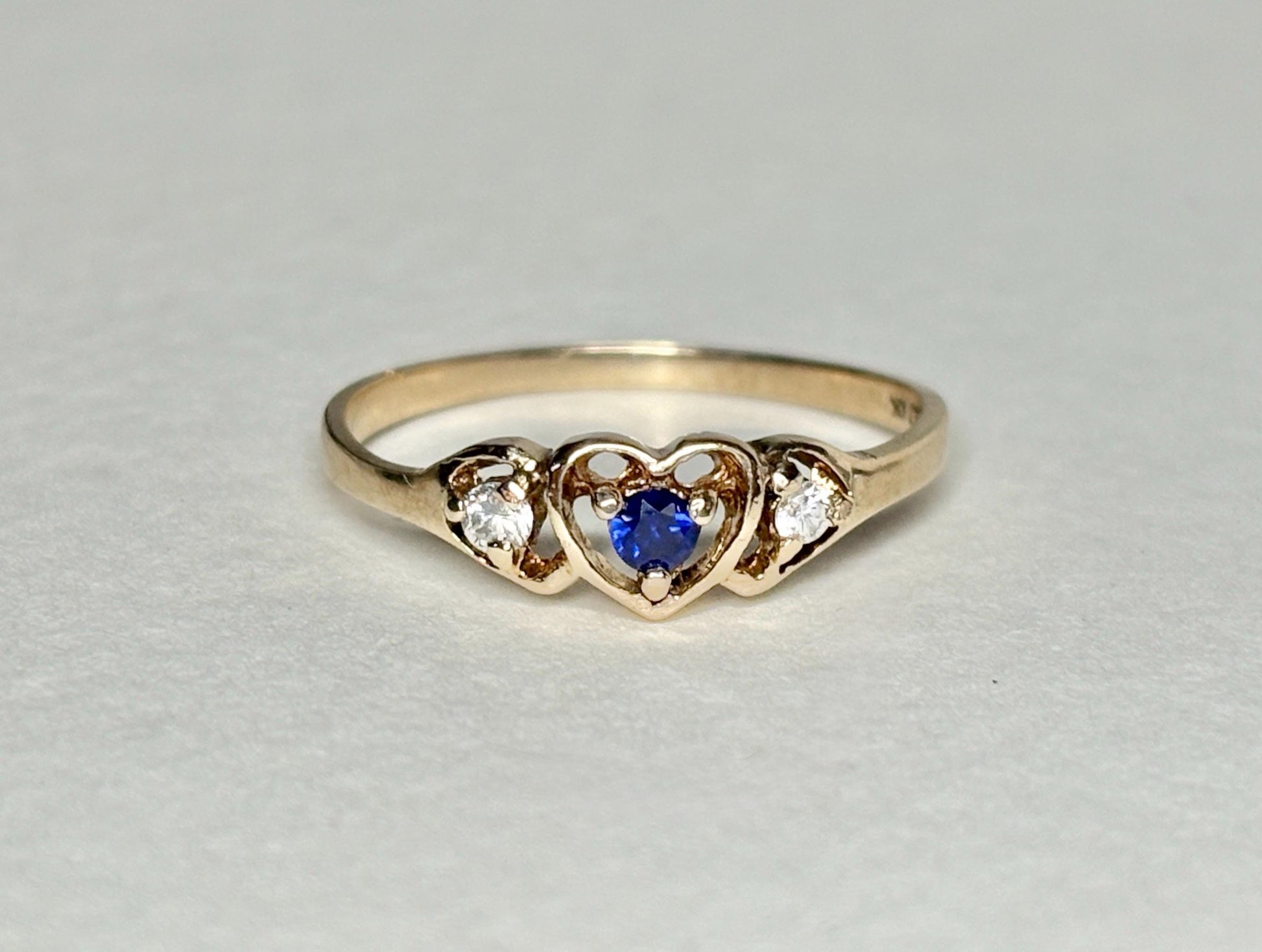 A vintage 10k gold heart band ring with a blue sapphire and two diamonds.