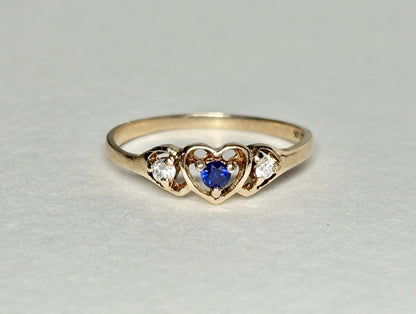 A vintage 10k gold heart band ring with a blue sapphire and two diamonds.