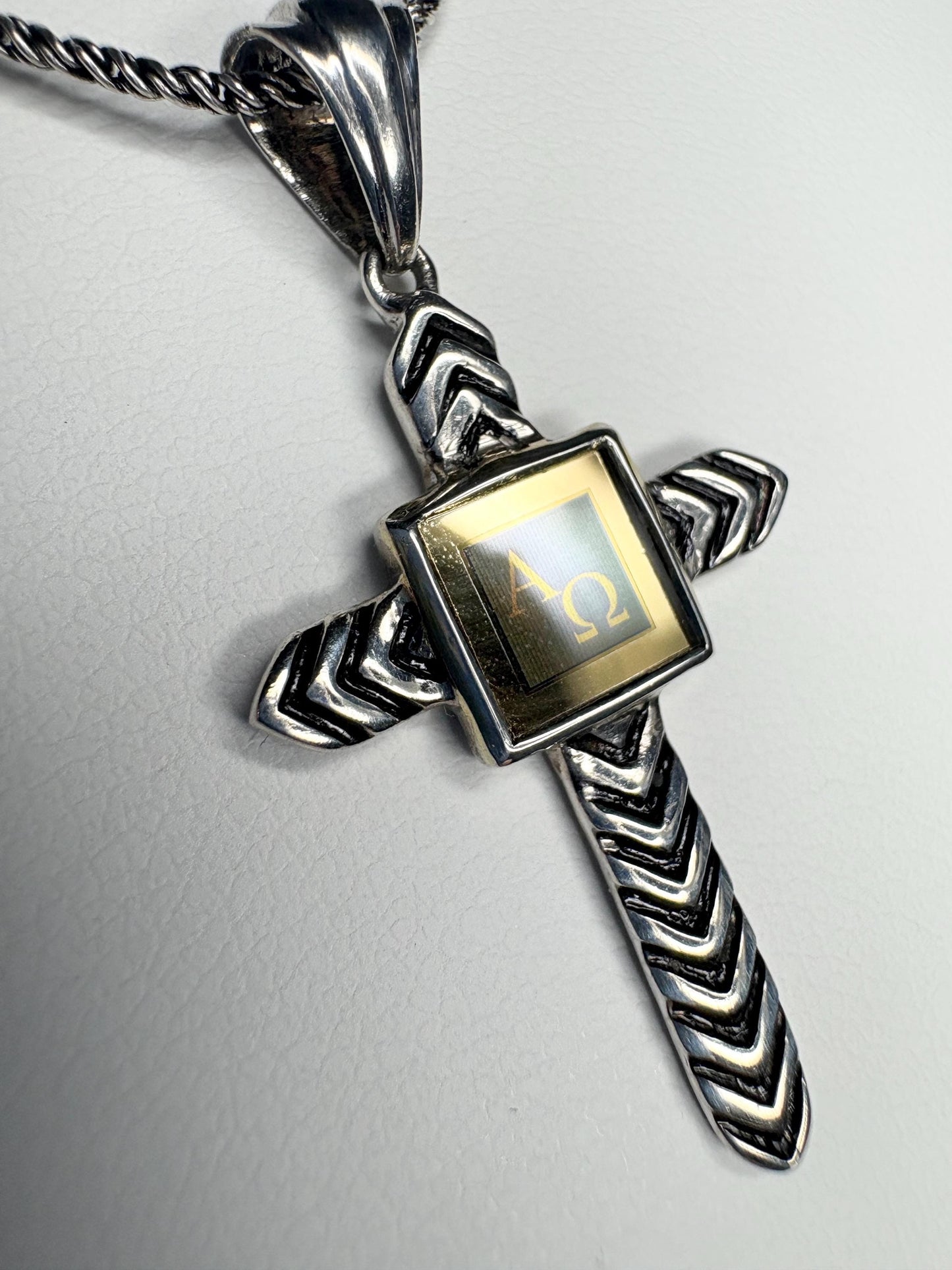 Sterling silver cross pendant with Alpha Omega symbols on a twisted chain.
