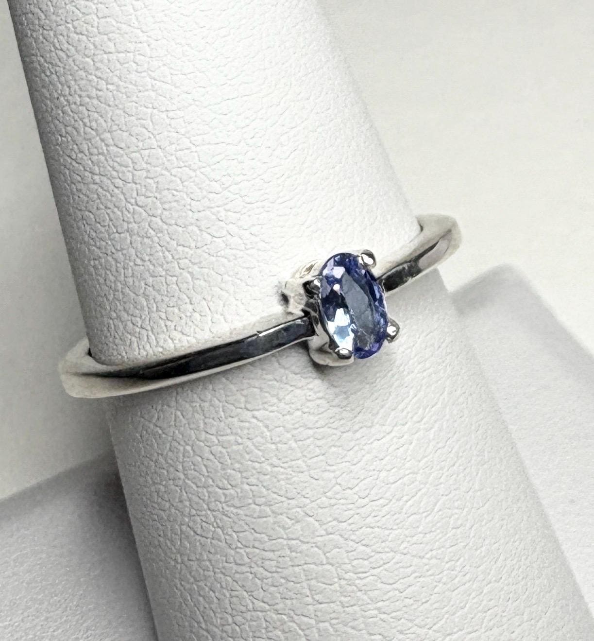 Sterling silver ring with a small oval tanzanite gemstone.