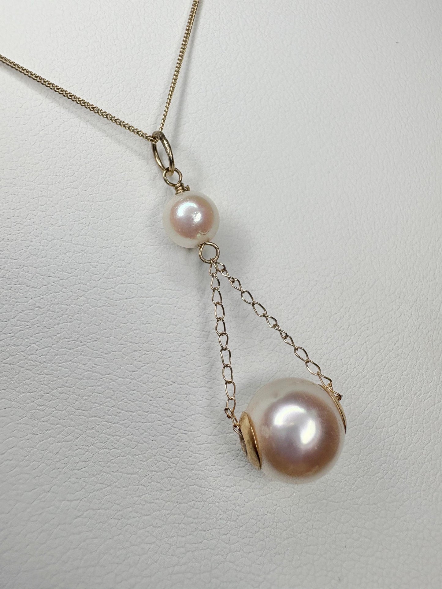 A gold lavaliere pendant necklace with two Akoya cultured pearls.