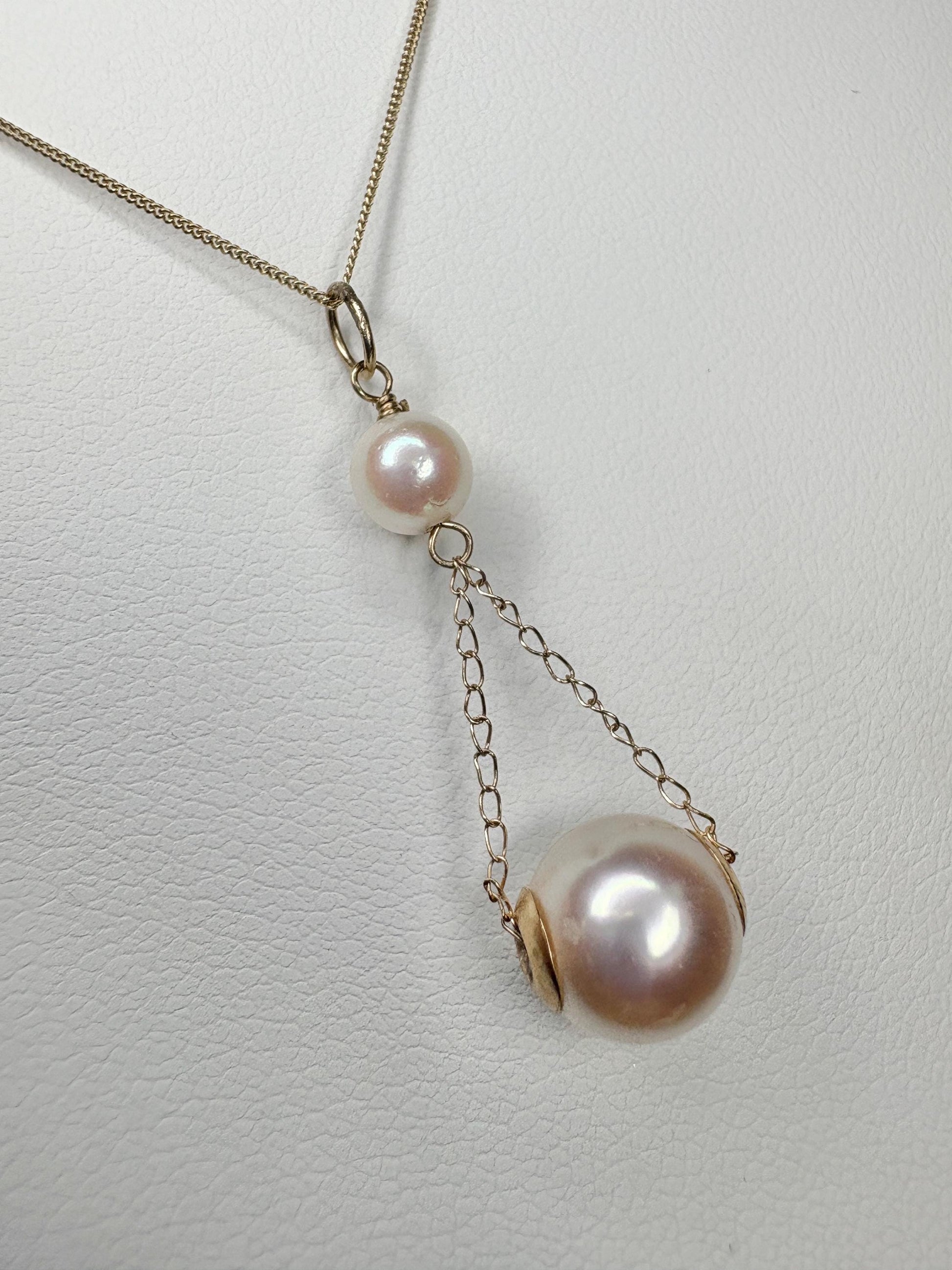 A gold lavaliere pendant necklace with two Akoya cultured pearls.
