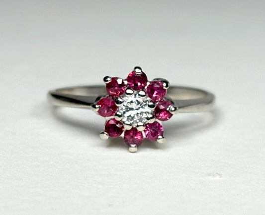 14k white gold ring with a diamond center and ruby daisy halo.