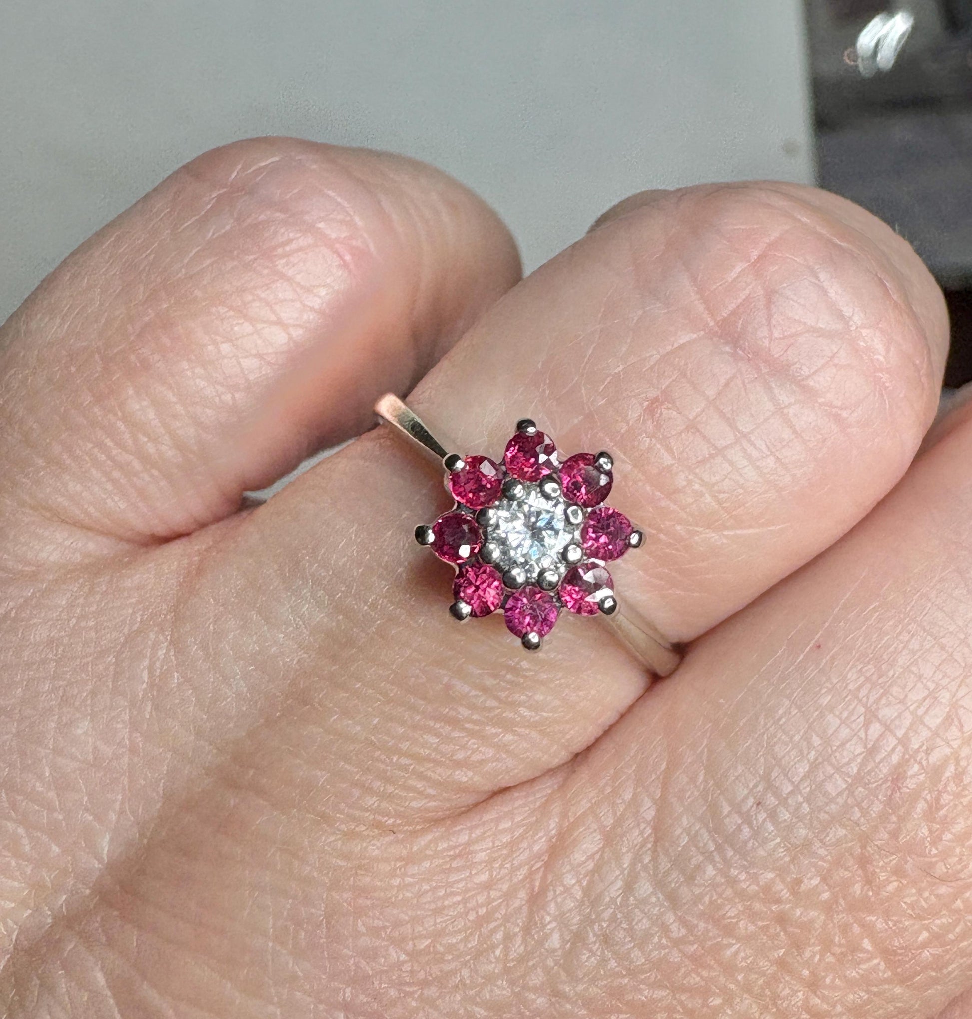 14k white gold ring with a diamond center and ruby halo.
