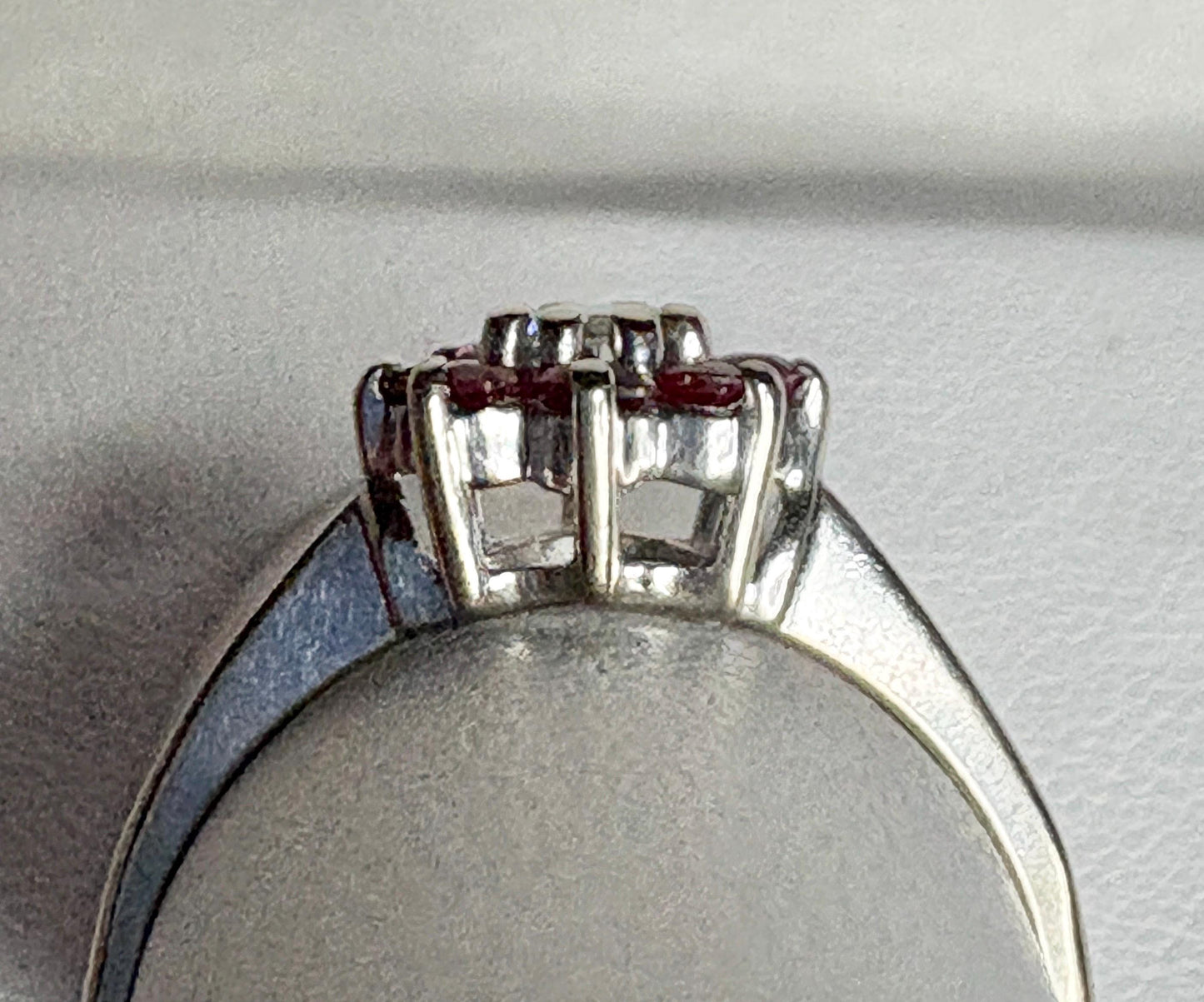 A 14k white gold ring with a ruby and diamond daisy halo design.