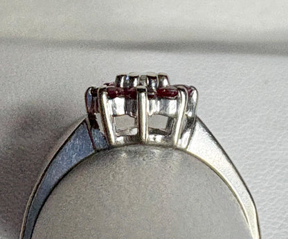 A 14k white gold ring with a ruby and diamond daisy halo design.