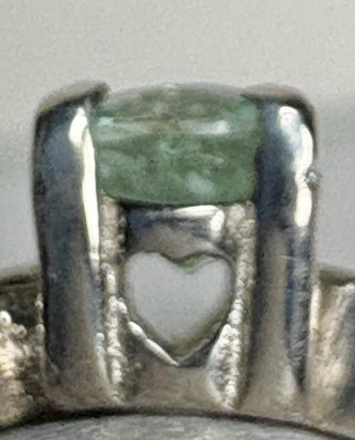 Sterling silver ring with a mint green oval tourmaline and a heart detail.