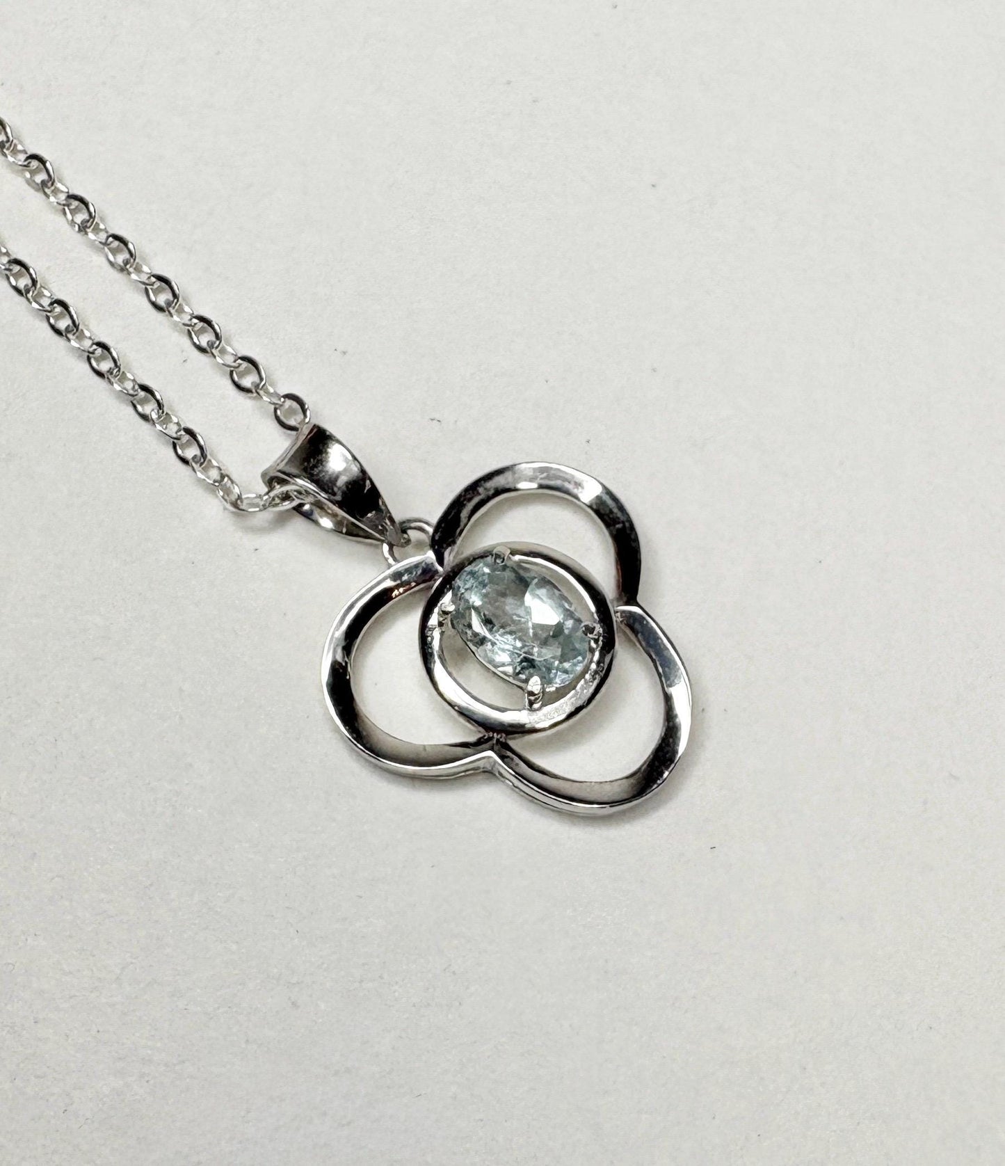 Sterling silver pendant necklace with a clover design and a light blue oval tourmaline.