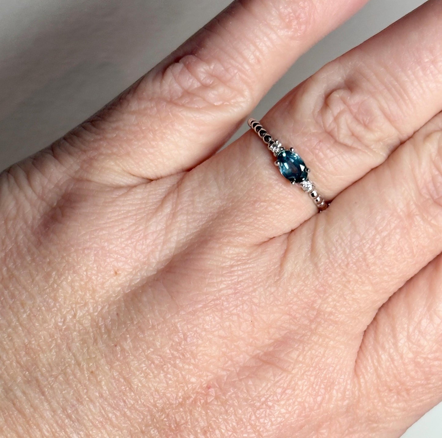 Sterling silver ring with oval Montana sapphire and two diamonds on a beaded band.