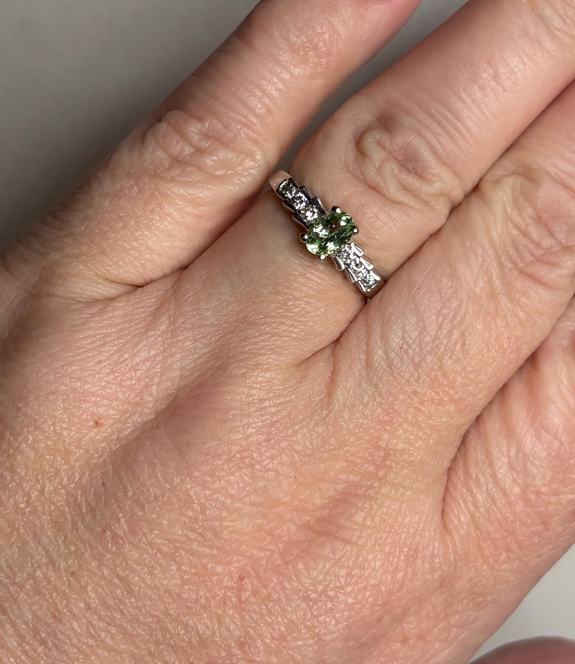 A 14k white gold ring with a green tourmaline and diamonds.