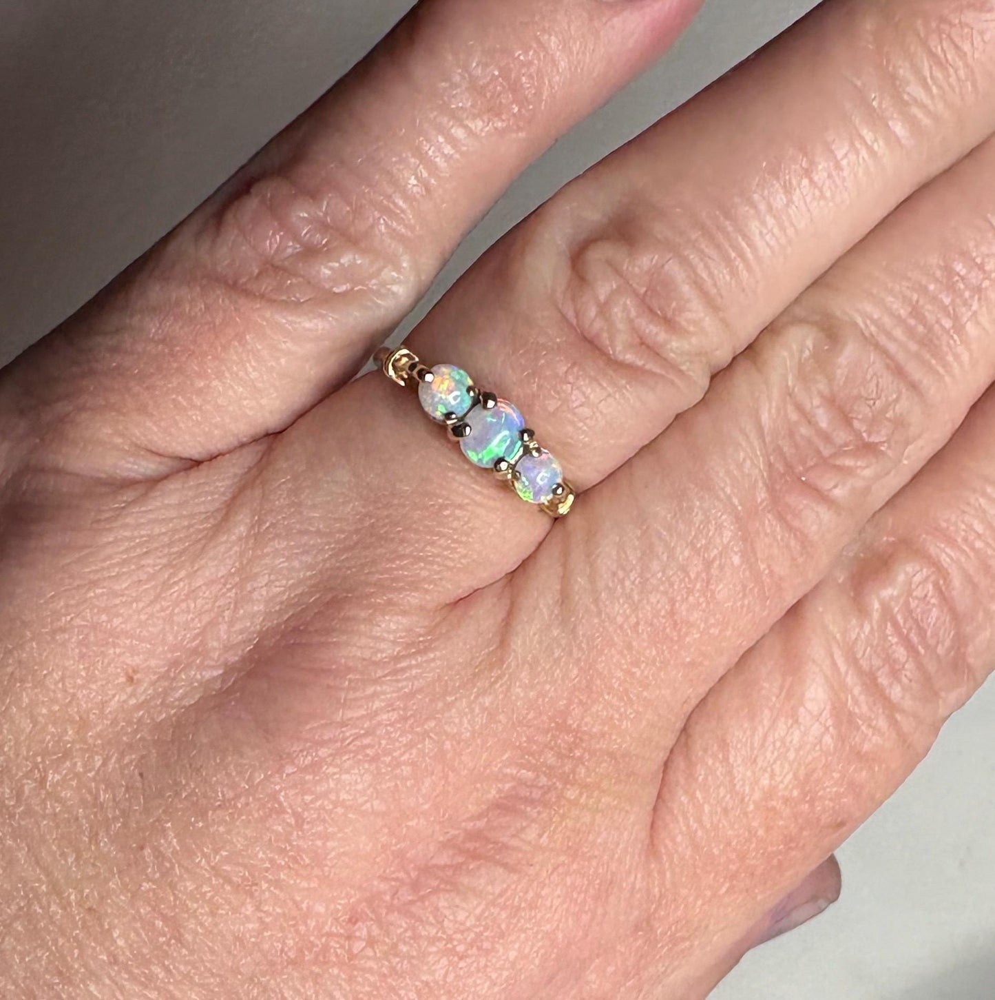 A 14k gold ring with three round opals.