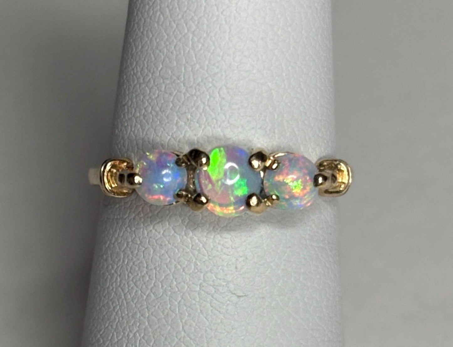 A 14k gold ring with three round opals.