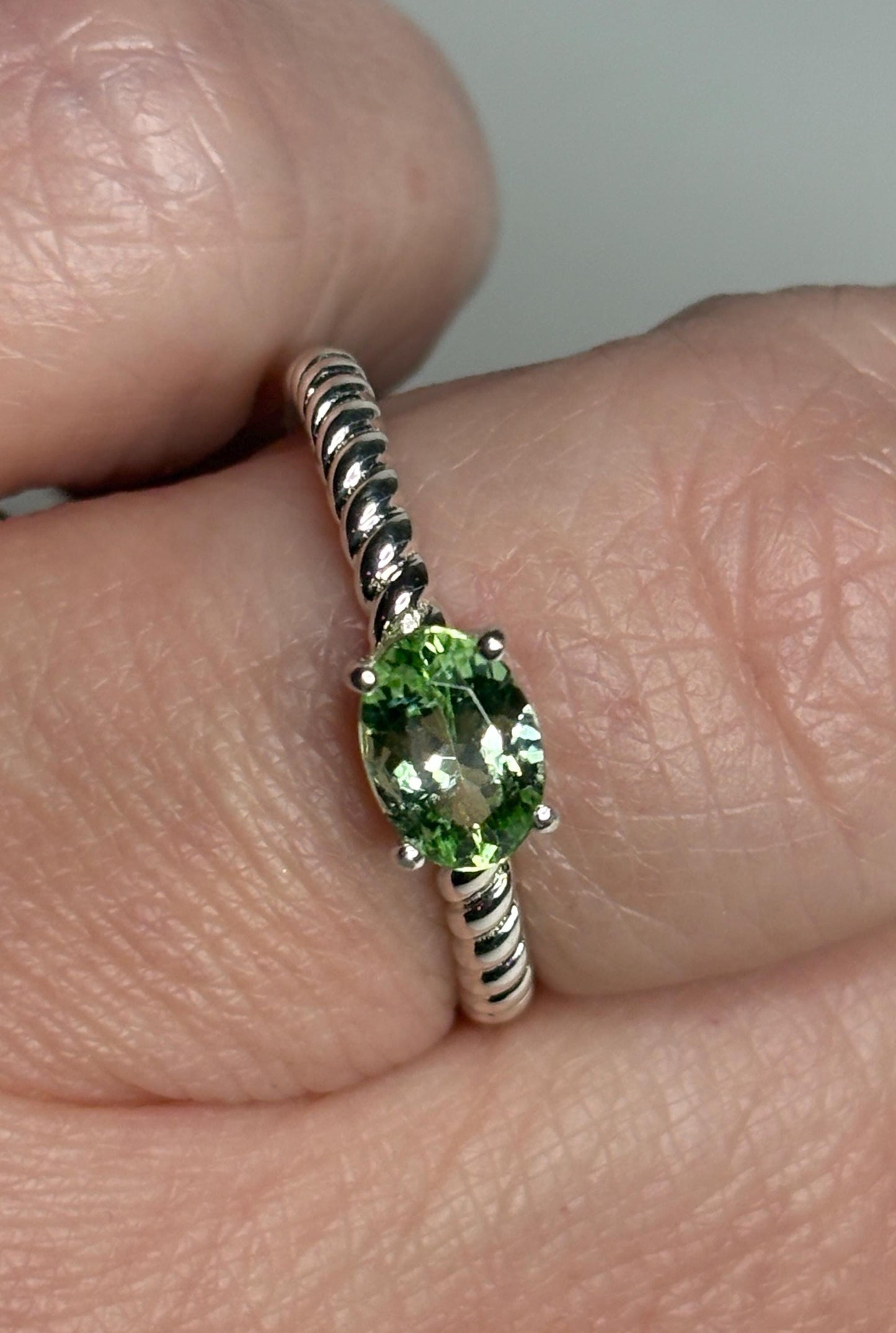 Sterling silver ring with an oval green tourmaline solitaire on a rope band.